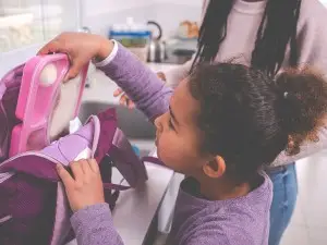 Girl packing bento box lunch into bookbag