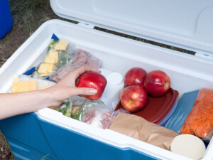 Woman reaching into cooler for an apple.