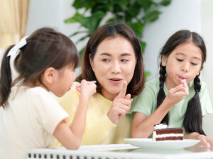 Mother telling daughters to have one piece of cake